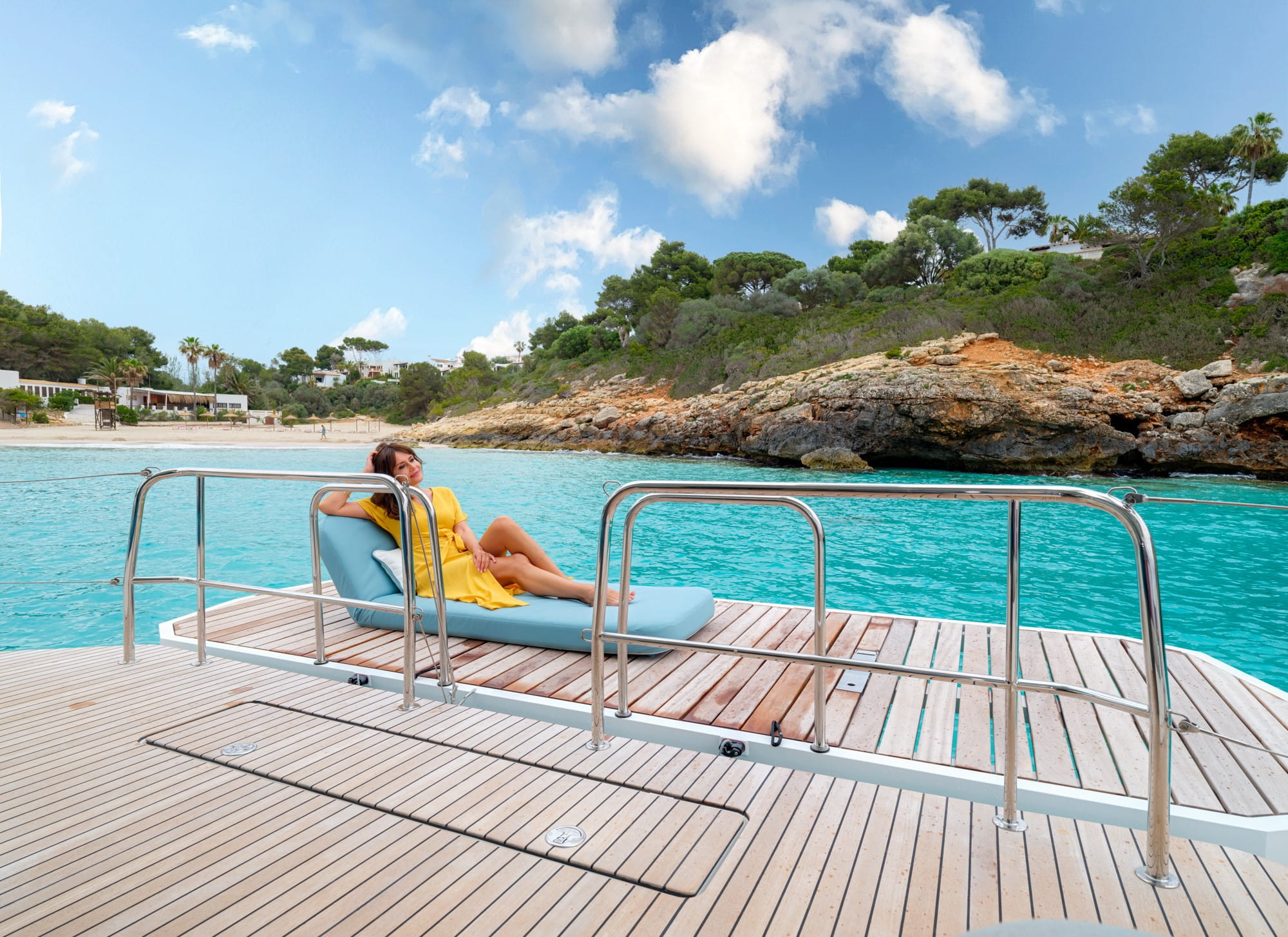 Invitée se relaxant sur le pont arrière du catamaran Lagoon 55 au mouillage dans une eau turquoise